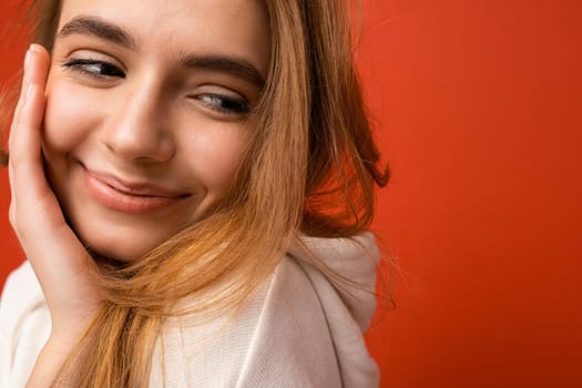 Portrait photo of young attractive dark blonde female person with sincere emotions isolated on background wall with copy space wearing casual white hoodie. Happy concept.