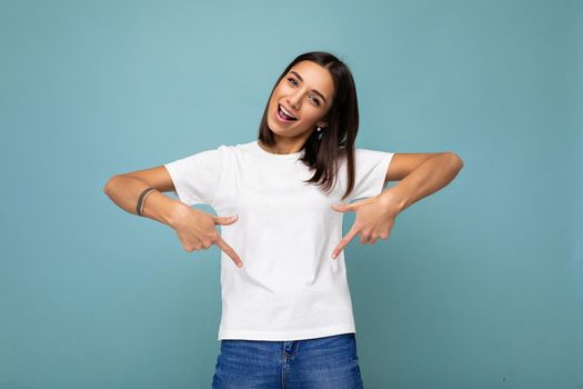 Photo of attractive positive surprised young woman pointing fingers down at copyspace presenting ads promo with wow omg sincere emotions wearing good look outfit isolated over background with free space.