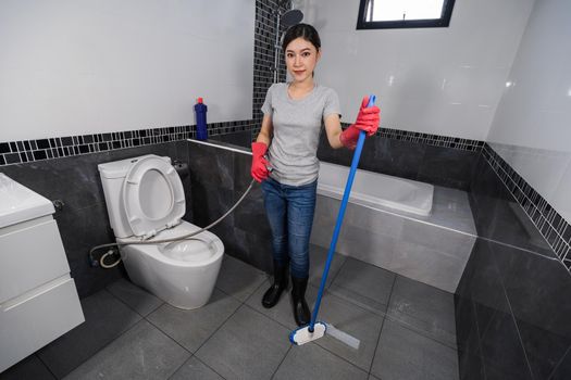 woman using brush to cleaning the tile in the bathroom