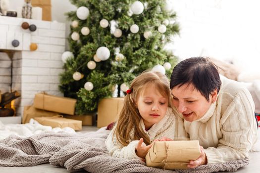 Mother and daughter unwrapping a present lying on the floor in the living room.