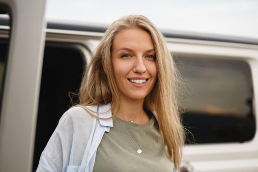 Portrait of happy young caucasian girl posing near off-road car, close up