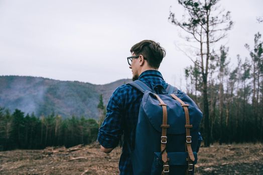 Hiker young man with backpack walking in the forest