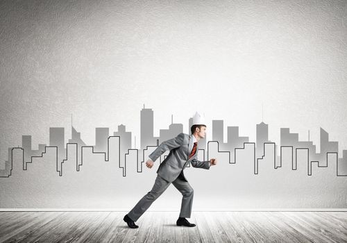 Young handsome businessman wearing white paper crown running in a hurry