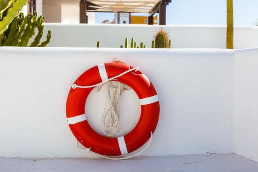 Red lifebuoy with white strip hanging on white wall , had space on left side for creative.