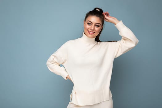 Lovely young woman wearing warm sweater standing isolated over blue background, posing. Joy and fun concept.