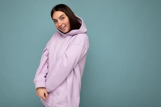 Young cute sttractive brunette woman with sincere emotions isolated on background wall with copy space wearing stylish purple hoodie. Happy cute concept.