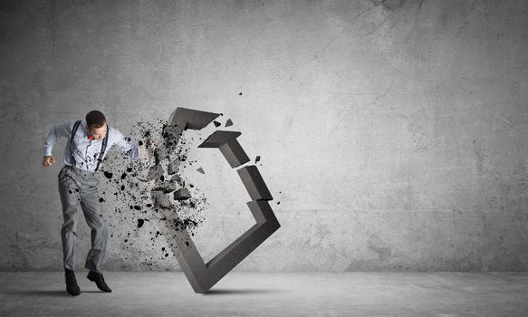 Determined businessman jumping and breaking with fist house concrete figure