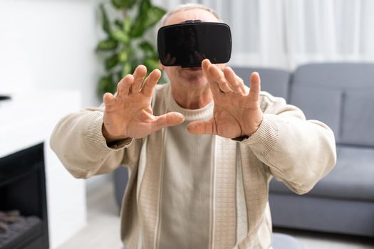 Portrait of senior man sitting on the sofa while playing video game with virtual reality glasses.