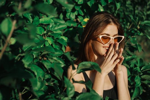 cheerful fashionable woman in sunglasses and green leaves summer luxury. High quality photo