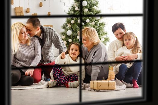 Big family with three children celebrating Christmas at home. Festive dinner at fireplace and Xmas tree. Parent and kids eating at fire place in decorated room. Child lighting advent wreath candle