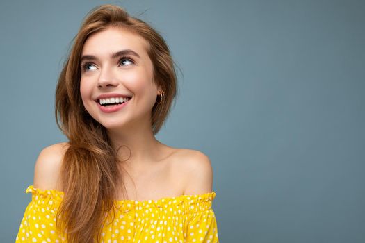 Closeup photo of young delightful smiling beautiful dark blonde woman with sincere emotions isolated on background wall with copy space wearing stylish summer yellow dress. Positive concept.