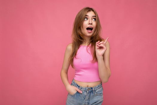 Young thoughtful beautiful dark blonde woman with sincere emotions isolated on background wall with copy space wearing stylish pink top. Idea concept.