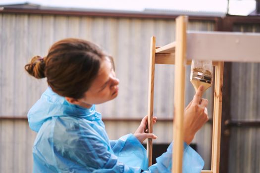 cheerful woman with a paint brush to paint wooden fittings. High quality photo