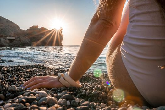 Young woman in swimsuit with long hair practicing stretching outdoors on yoga mat by the sea on a sunny day. Women's yoga fitness pilates routine. Healthy lifestyle, harmony and meditation concept.