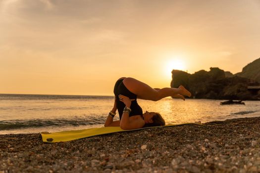 Young woman in swimsuit with long hair practicing stretching outdoors on yoga mat by the sea on a sunny day. Women's yoga fitness pilates routine. Healthy lifestyle, harmony and meditation concept.