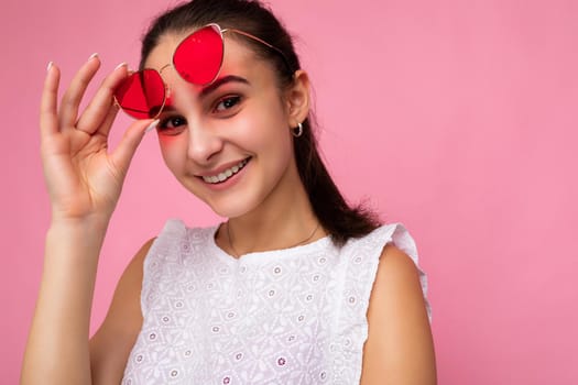 Closeup photo shot of beautiful positive young brunette woman wearing summer casual clothes and stylish sunglasses isolated over colorful background wall looking at camera.
