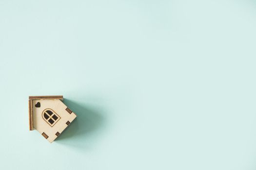 Concept of self-quarantine at home as a preventive measure against an outbreak of the virus. Flat lay with an inspired quote, staying at home during the pandemic. Wooden house on a mint background.