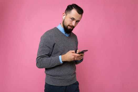 Handsome man over pink background sending a message with the mobile.