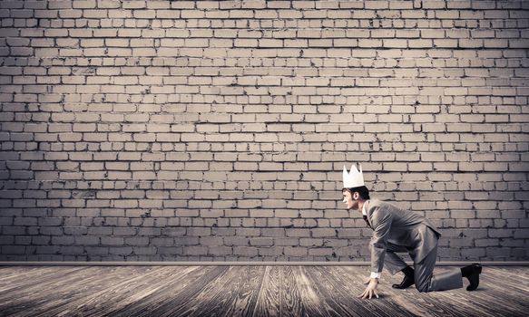 Young handsome businessman wearing white paper crown running in a hurry