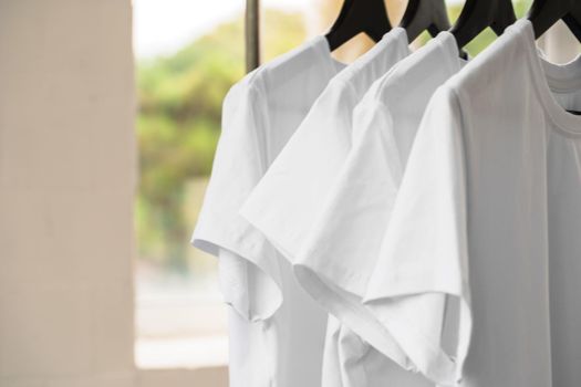 Row of white t-shirts on hangers hanging on rack