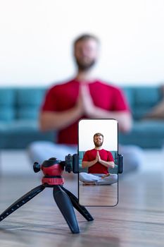 Vertical photo - live streaming on a smartphone. Online yoga lesson. Focus on smartphone.