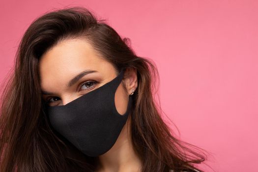Shot of young attractive woman wearing mediacal face mask isolated over background wall. Protection against COVID-19. Free space
