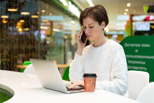 student working at a laptop in a cafe in a shopping center, concept of freelancing and remote work.