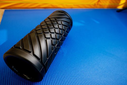 Sport fitness foam roller on blue mat, close up