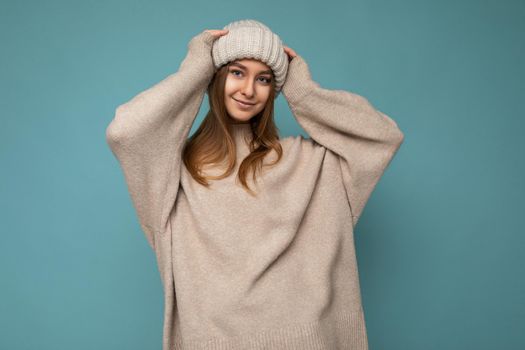 Attractive smiling happy young brunet woman standing isolated over colorful background wall wearing everyday stylish outfit showing facial emotions looking at camera.