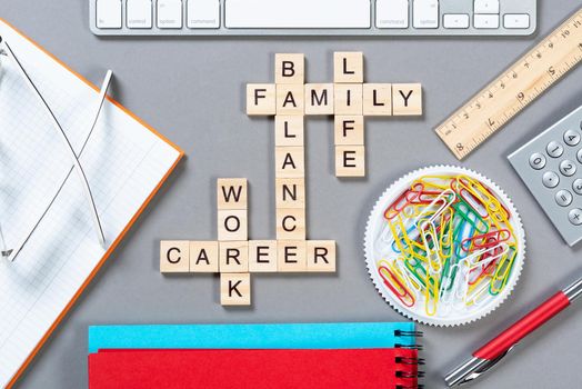 Business motivation concept with words from cubes. Still life of office workplace with crossword. Flat lay grey surface with computer keyboard and stationery. Strategy planning and business analytics.