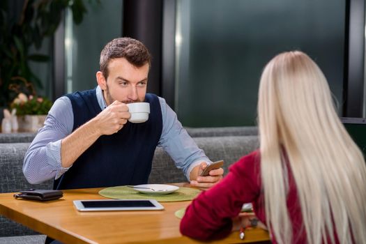 A woman and a man on a business lunch in a restaurant, drink coffee