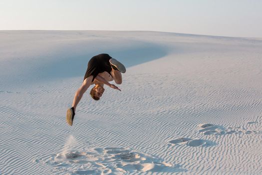 Man study parkour on their own. Acrobatics in the sand. Flip on the sand