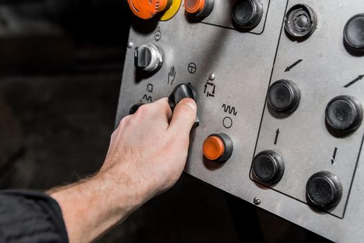 Human hand uses old control panel of industrial equipment in the factory.
