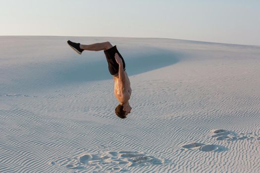 Man study parkour on their own. Acrobatics in the sand. Flip on the sand