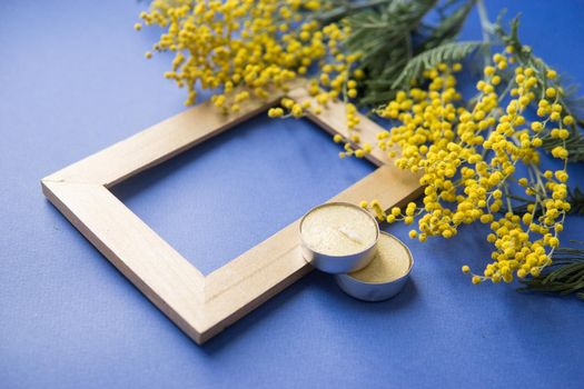 Spring concert. Mimosa and gold frame on blue background. Mimosa close-up. Happy spring. Space for text.