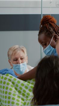 Caucasian family in childbirth labor getting medical assistance in hospital ward bed. Obstetrics doctor and african american nurse helping pregnant woman pushing for child delivery