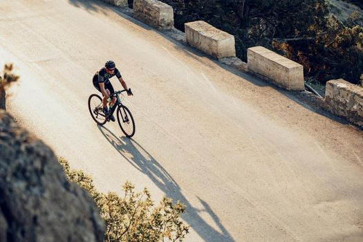 Professional man cyclist on a mountain road at sunrise