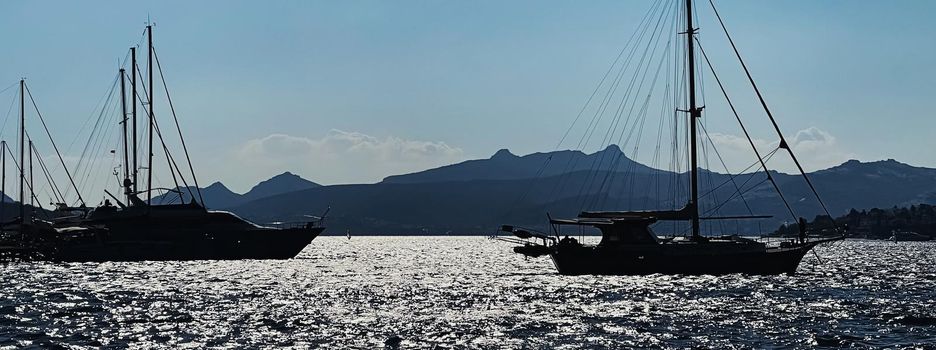 Tranquil seascape and coastal nature concept. Sea, boats, mountains and blue sky over horizon at sunset.