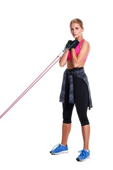 Strong woman using a resistance band in her exercise routine. Young woman performs fitness exercises on white background. Woman with beautiful slim healthy body posing in studio.