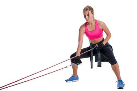Strong woman using a resistance band in her exercise routine. Young woman performs fitness exercises on white background. Woman with beautiful slim healthy body posing in studio.
