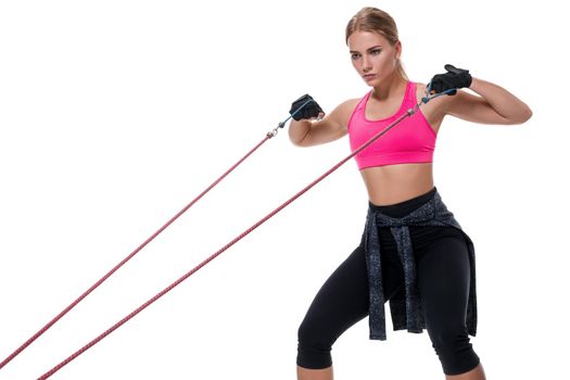 Strong woman using a resistance band in her exercise routine. Young woman performs fitness exercises on white background. Woman with beautiful slim healthy body posing in studio.