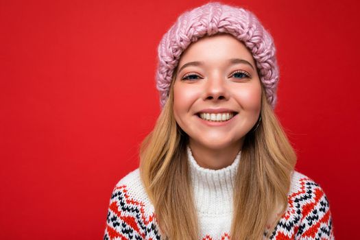 Closeup photo of beautiful happy smiling young blonde woman standing isolated over colourful background wall wearing everyday trendy clothes looking at camera showing facial emotions.