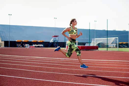 Beautiful young woman exercise jogging and running on athletic track on stadium. Red treadmill in sport field.