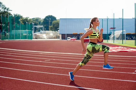 Beautiful young woman exercise jogging and running on athletic track on stadium. Red treadmill in sport field.