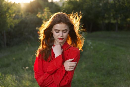 cheerful woman in a red dress in a field outdoors fresh air. High quality photo