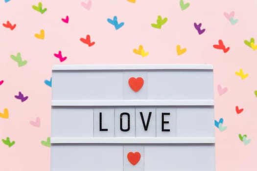 Valentine's Day composition with picture frame with text 'LOVE', cupid love arrows, letter, and hearts on red background