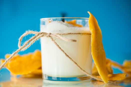 homemade sweet yogurt in a glass with mango isolated on blue background