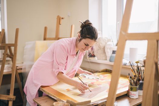 Art, creativity, hobby and creative occupation concept. Bringing creativity to life. Woman painting in art studio. Attractive female artist painting in workshop. Woman hobby, activity, profession.