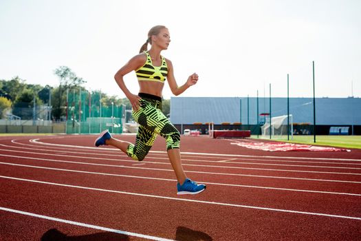Beautiful young woman exercise jogging and running on athletic track on stadium. Red treadmill in sport field.
