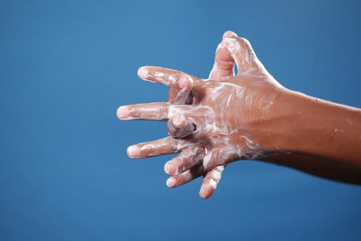 child boxy washing hands with soap on blue background .